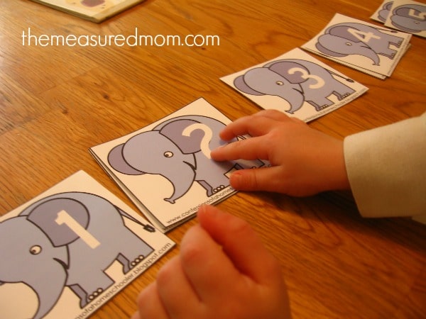 child practicing counting with numbered elephant cards