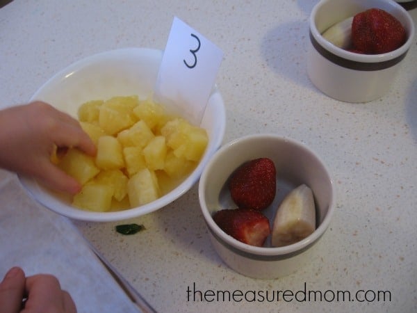 child taking pineapple out of bowl