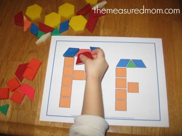 child placing shapes on block letter F card