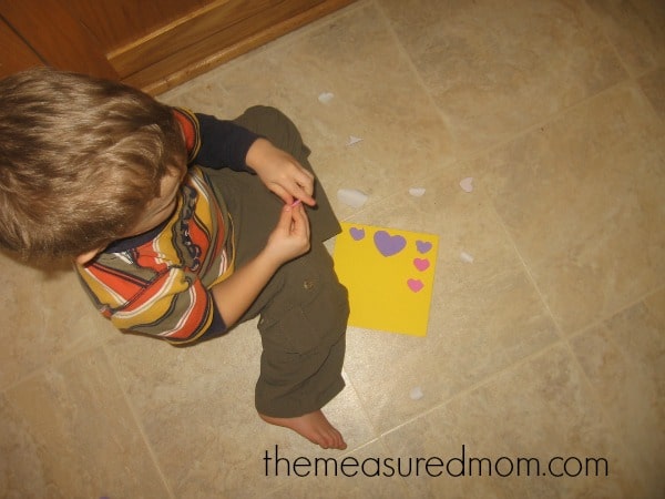 child placing heart stickers on paper