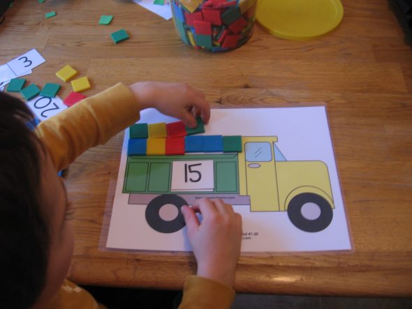 child with dump truck counting mat letter T
