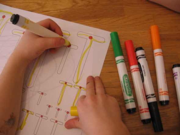 child writing on letter T worksheet