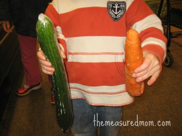child holding cucumber and carrot