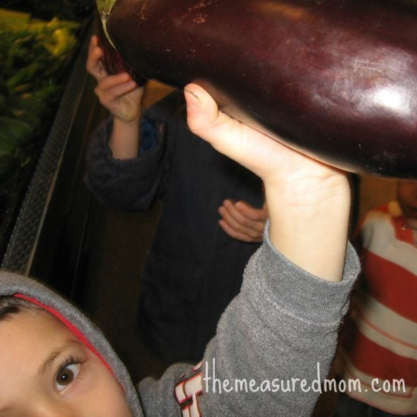 child holding up eggplant