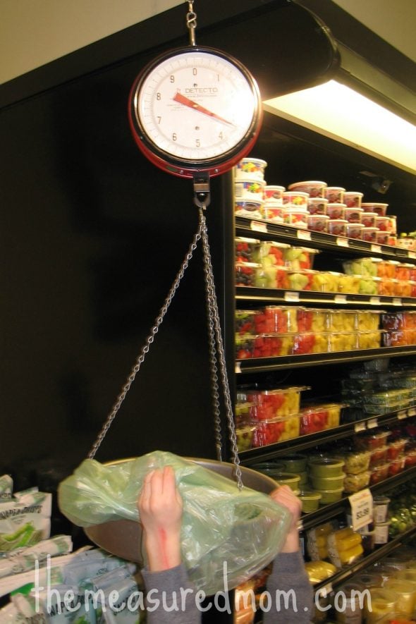 child putting something on grocery store scale 