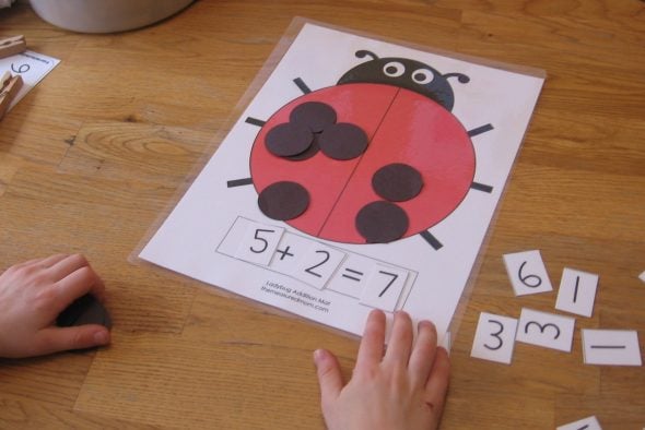 child practicing counting with ladybug addition mat