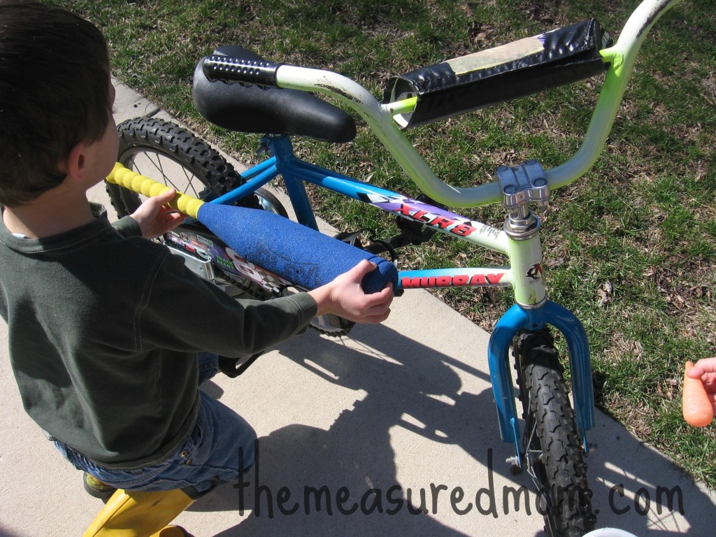 child comparing baseball bat to bike