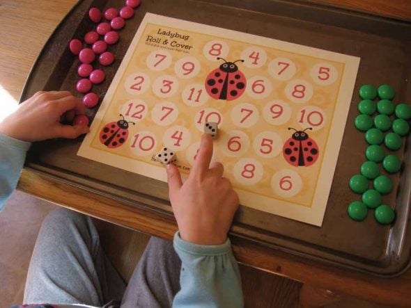child playing ladybug roll and cover addition game