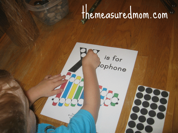 child placing dot stickers on X is for xylophone worksheet