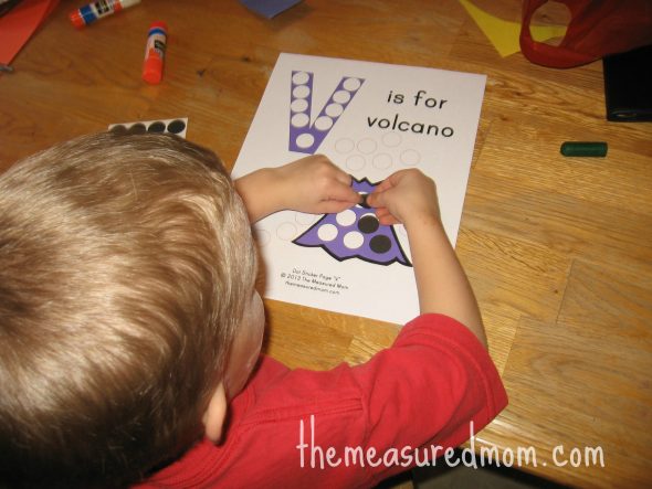 child placing dot stickers on V is for volcano worksheet