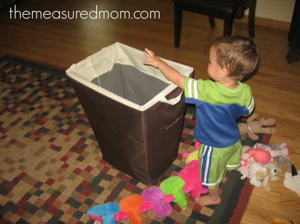 child tossing stuffed animals into hamper