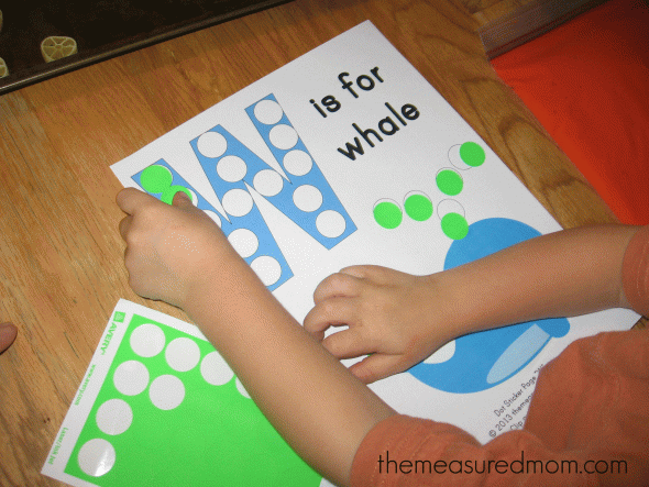 child placing dot stickers on W is for whale worksheet
