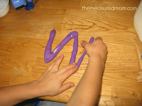 child making letter W with play dough worms