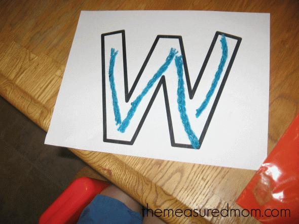 child with letter W outline filled with yarn strips