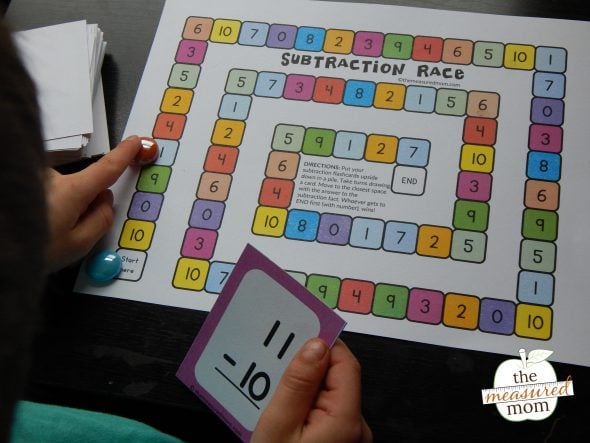 This simple subtraction activity will help kids in kindergarten and first grade practice their basic facts. The game includes free subtraction flash cards, too! #subtraction #kindergarten #mathfacts #subtractiongame child playing subtraction game