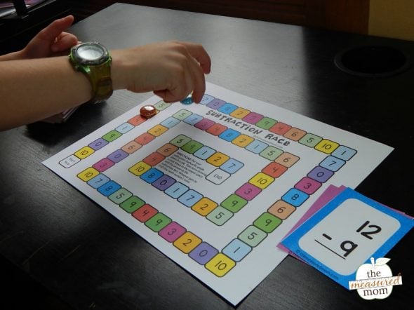 This simple subtraction activity will help kids in kindergarten and first grade practice their basic facts. The game includes free subtraction flash cards, too! #subtraction #kindergarten #mathfacts #subtractiongame child playing subtraction game